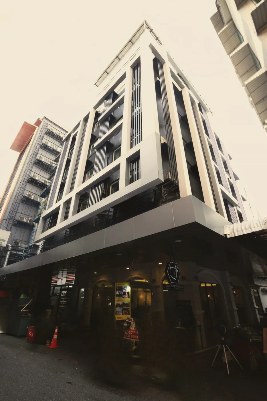 Sleepstation hotel building on a busy Pratunam street corner, with the hexagon sign above the entrance